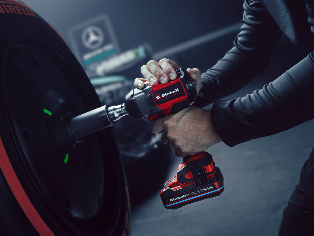 Einhell cordless impact wrench in use on a car wheel, with Mercedes-AMG Petronas Formula One Team branding and partnership logo