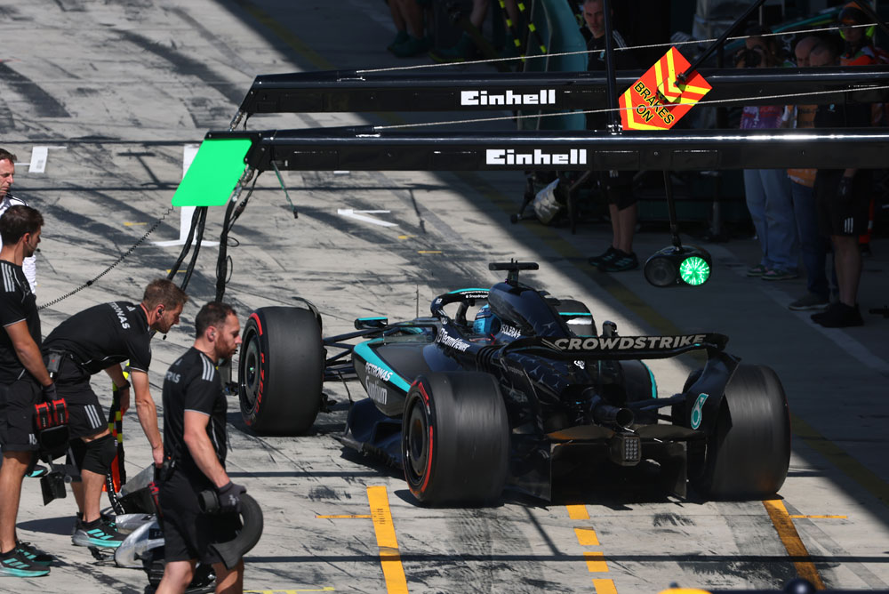 A Mercedes-AMG PETRONAS Formula One car in the pit lane during a pit stop. Several team members are around the car. The Einhell branding is visible above the pit area.