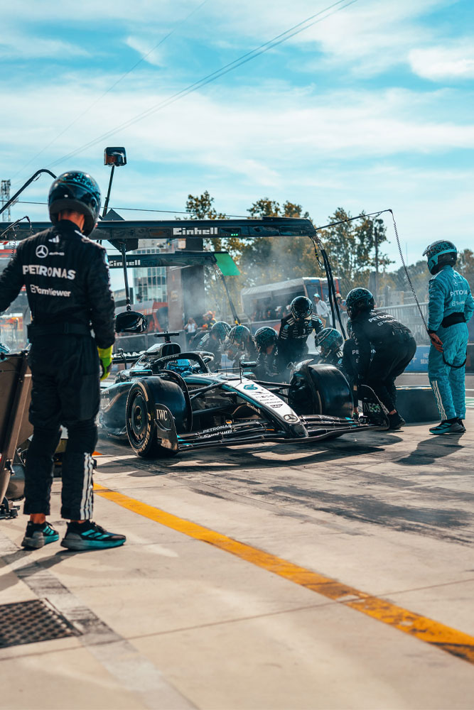 A high-intensity pit stop for the Mercedes-AMG PETRONAS Formula One Team. The crew is in action, changing tyres and checking the car under the Einhell-branded gantry.